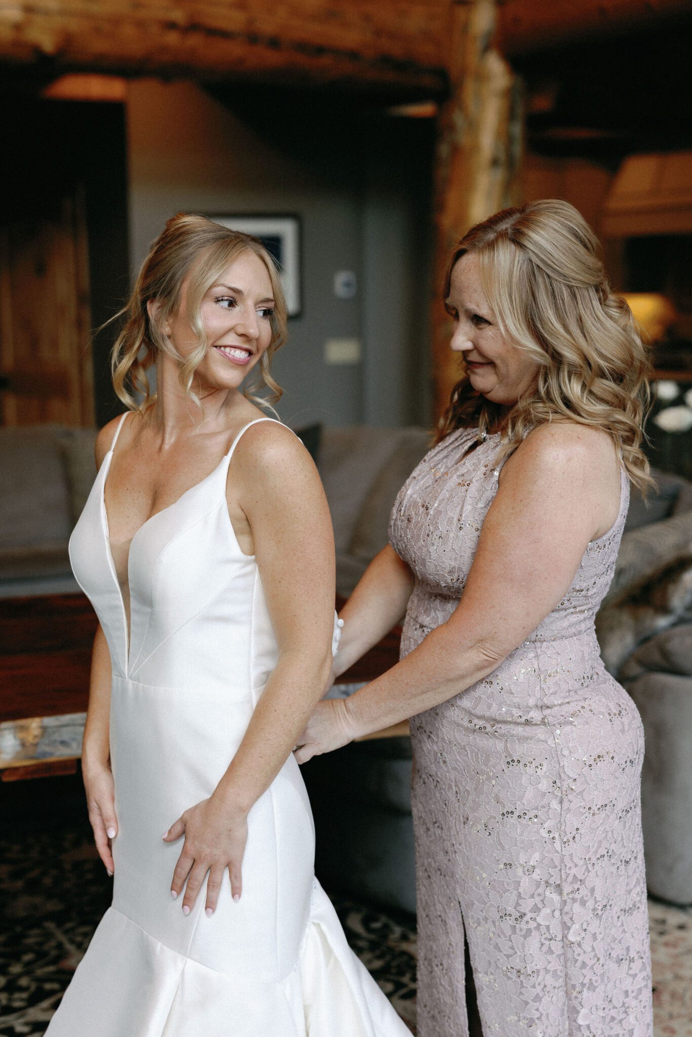 bride puts on wedding dress with the help of her mother