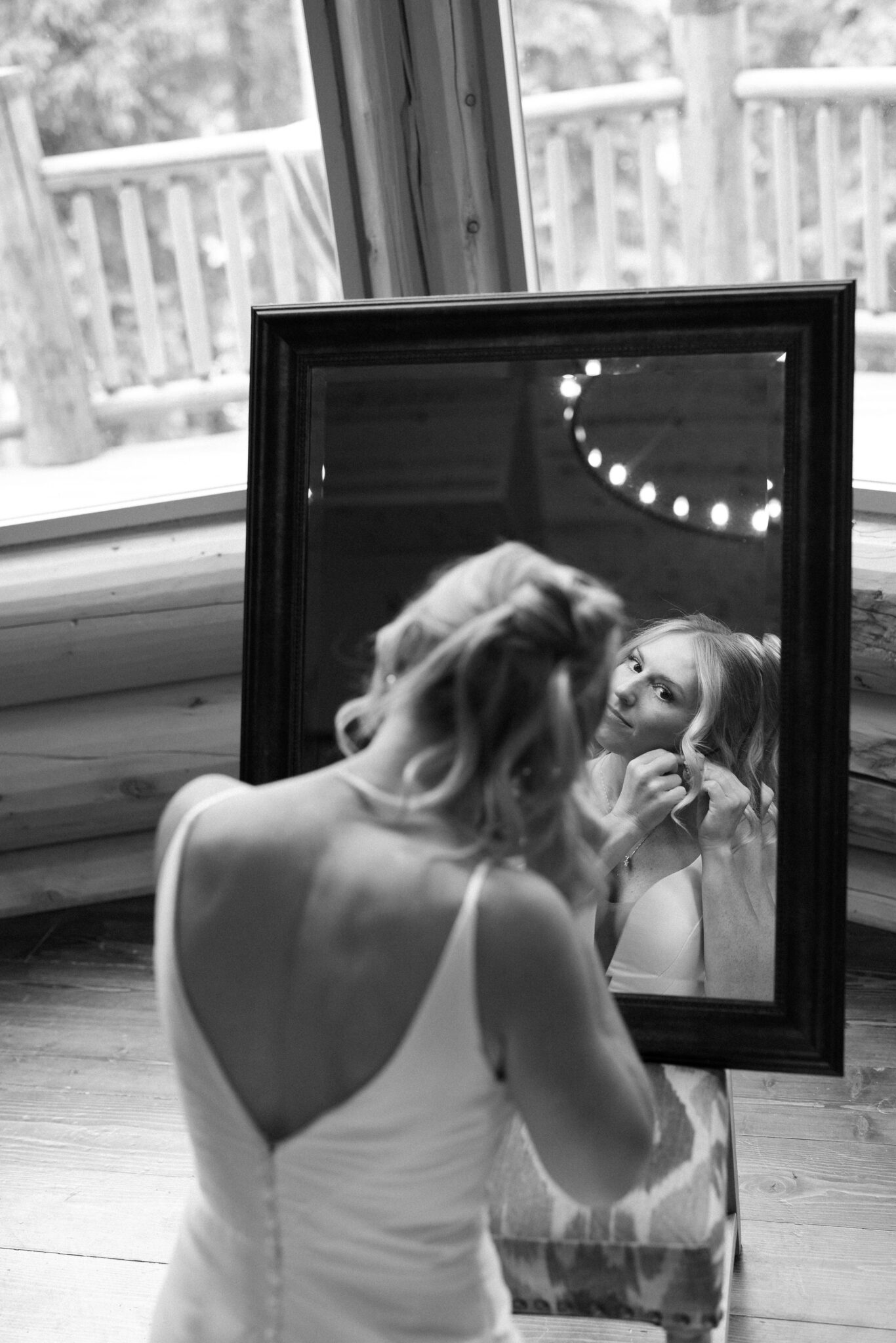 bride looks in the mirror as she puts her earrings on before her colorado airbnb wedding ceremony