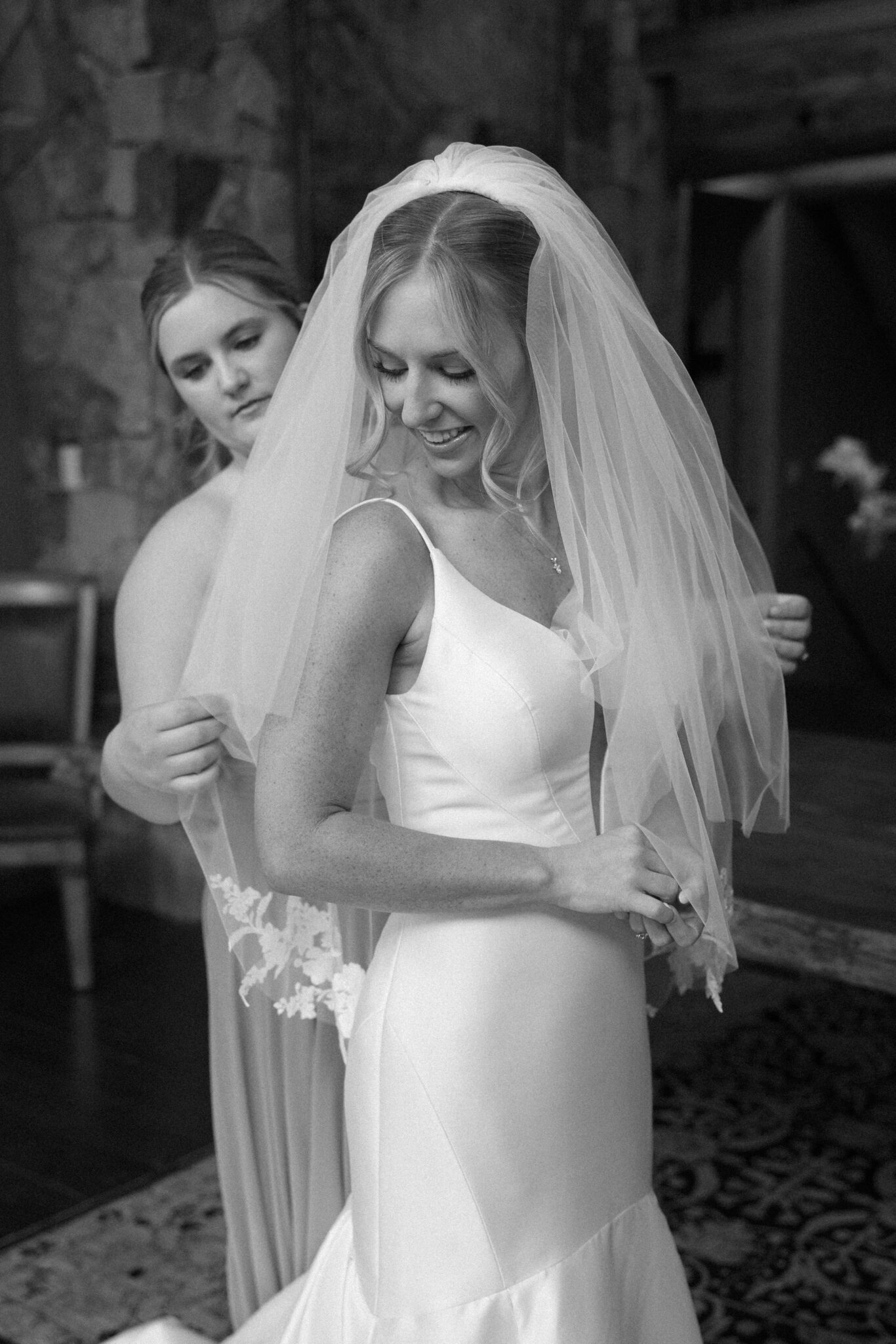 bridesmaid helps bride put her veil on before her wedding ceremony