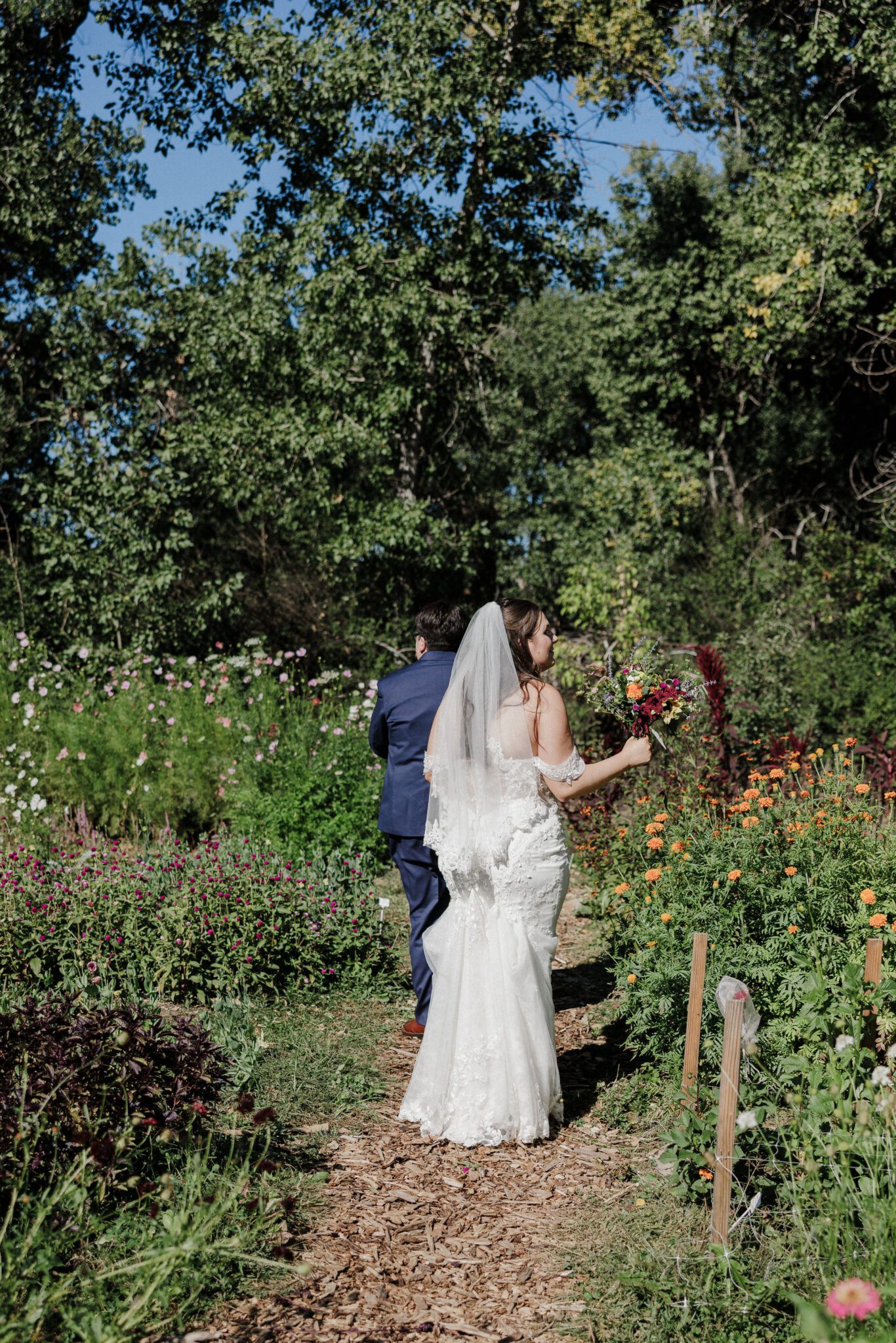 two brides walk through the flower farm they used as their colorado elopement location