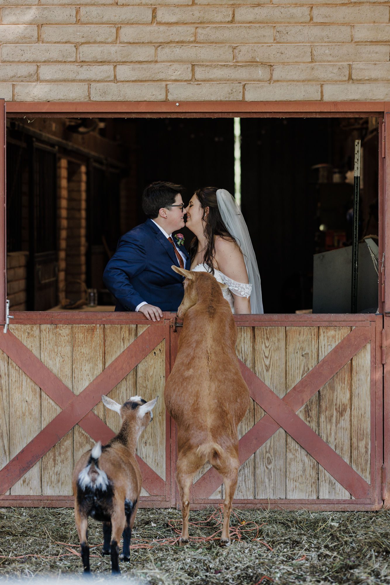 two brides kiss at the barn on the property of the private venue