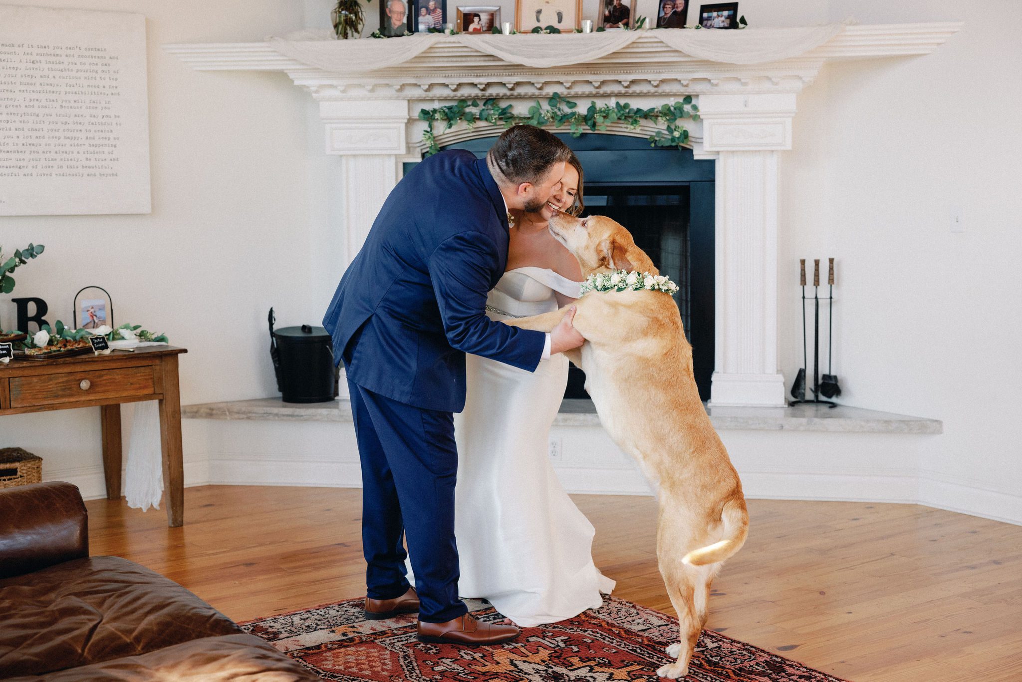 bride and groom dance while their dog jumps up for kisses