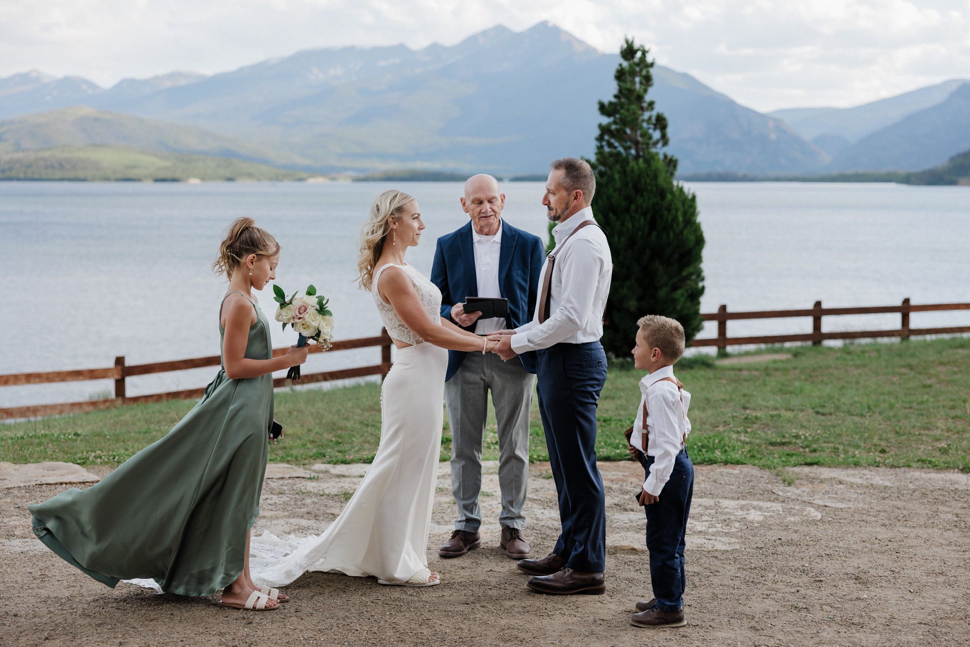 bride and groom stand with their family during a wedding cermeony at lake dillon, their colorado elopement location,