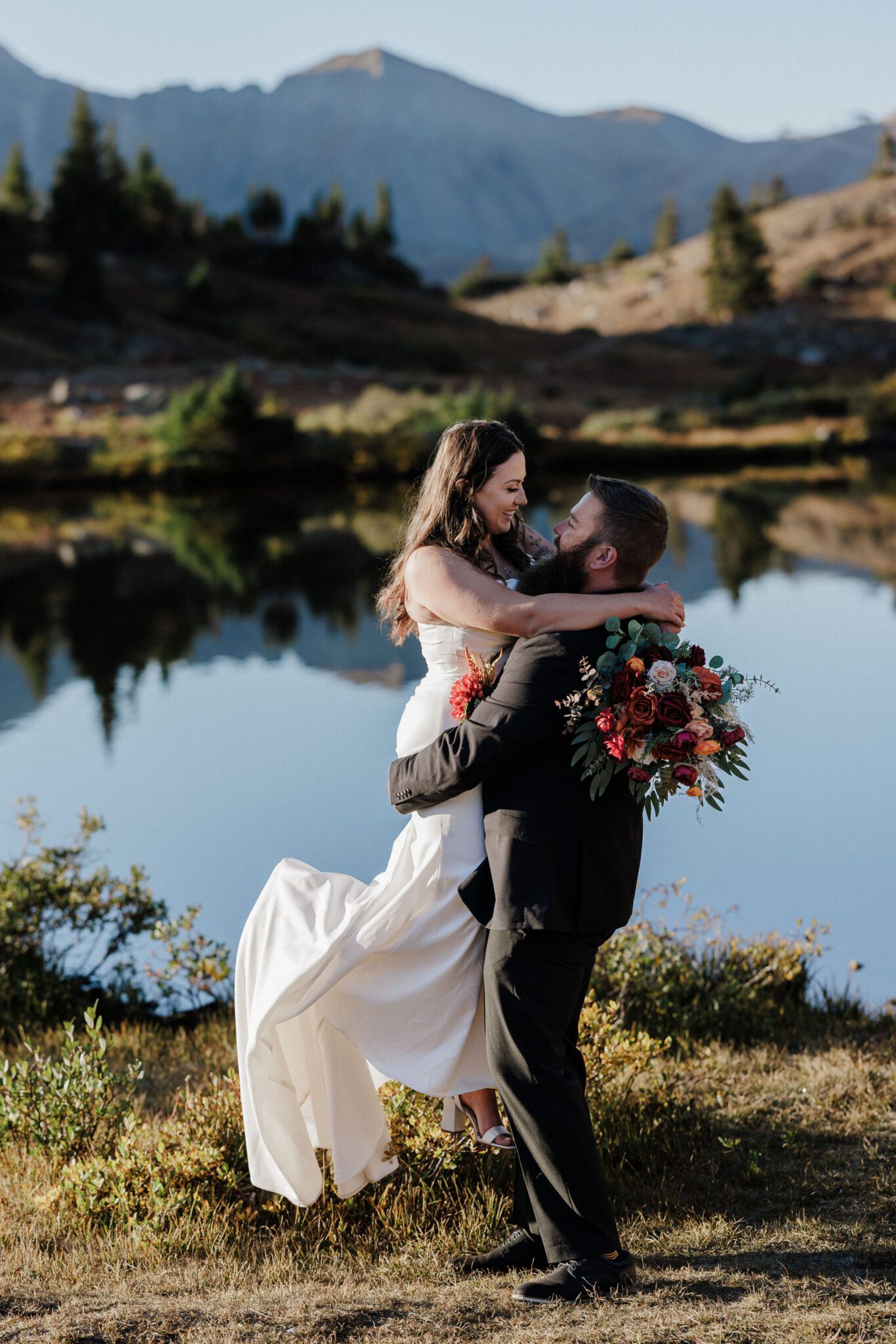 groom lifts up bride during elopement photos by pass lake, a colorado elopement location