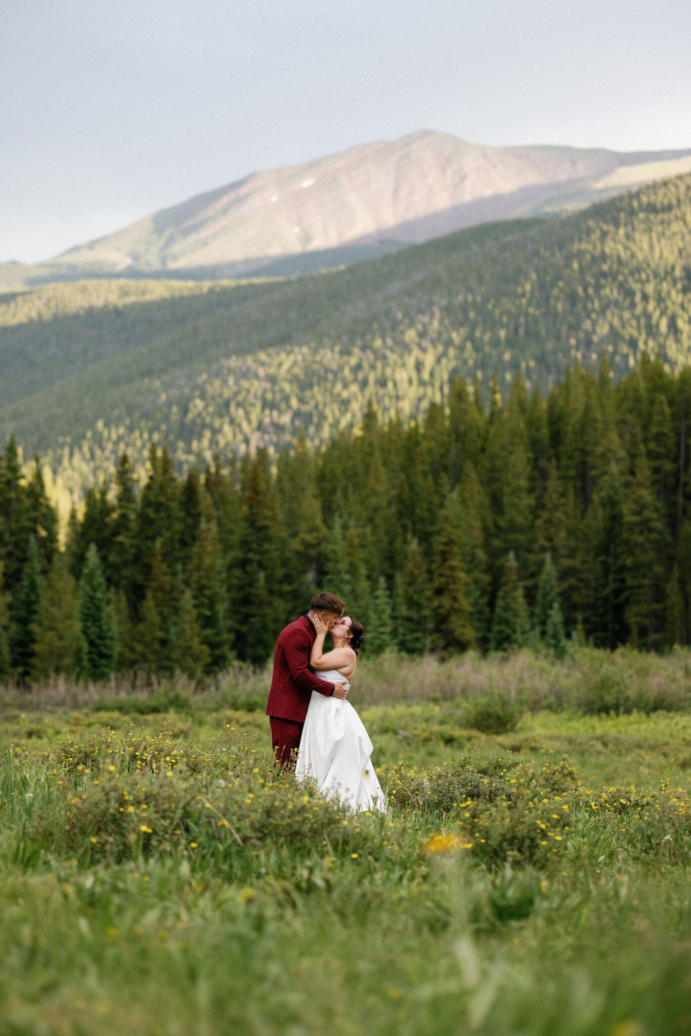 bride adn groom kiss in front of a mountain at boreas pass during their elopement