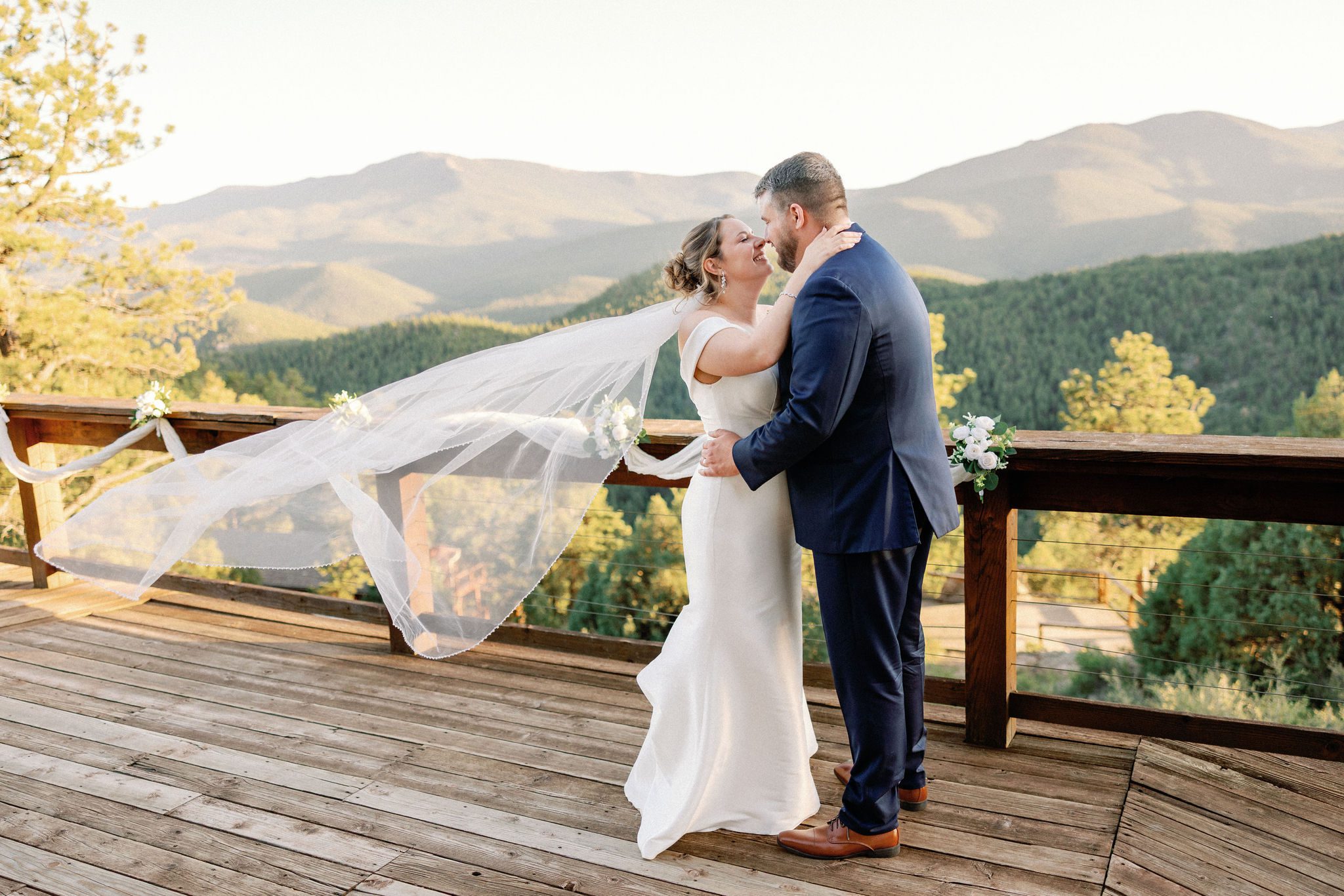 bride and groom pose for wedding photographer on the airbnb deck overlooking the colorado mountains